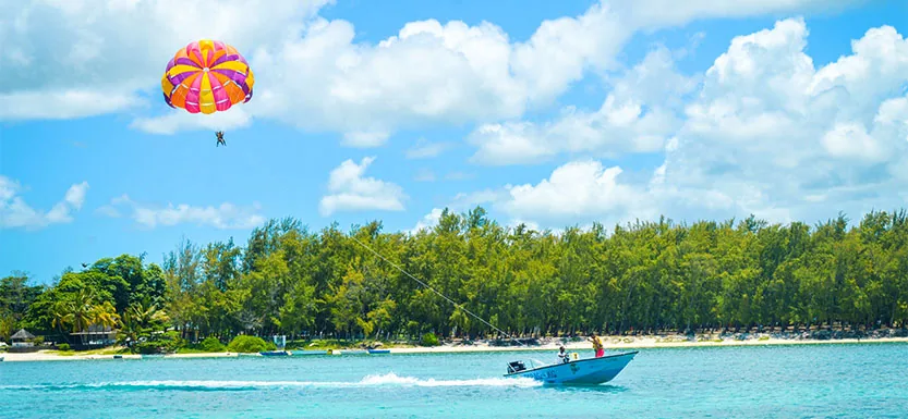 Parasailing over a turquoise lagoon beside a tropical beach