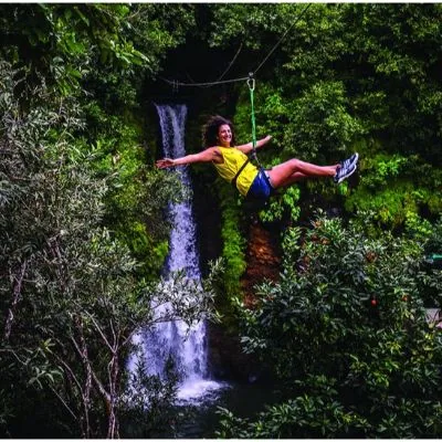 Zipline rider crossing in front of a waterfall